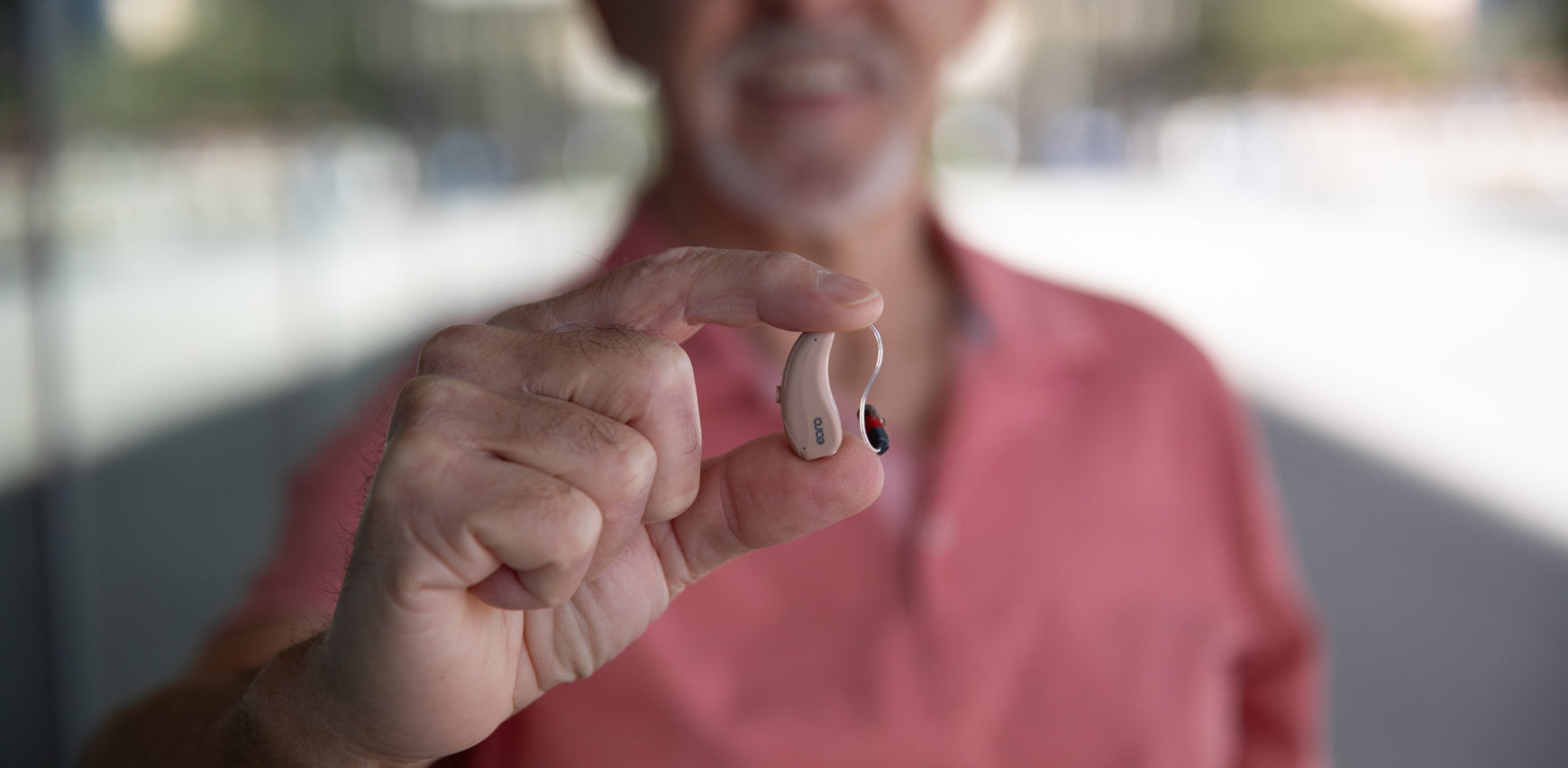 A man holding a pair of Eara OTC Bluetooth hearing aids, showcasing the compact and modern design.